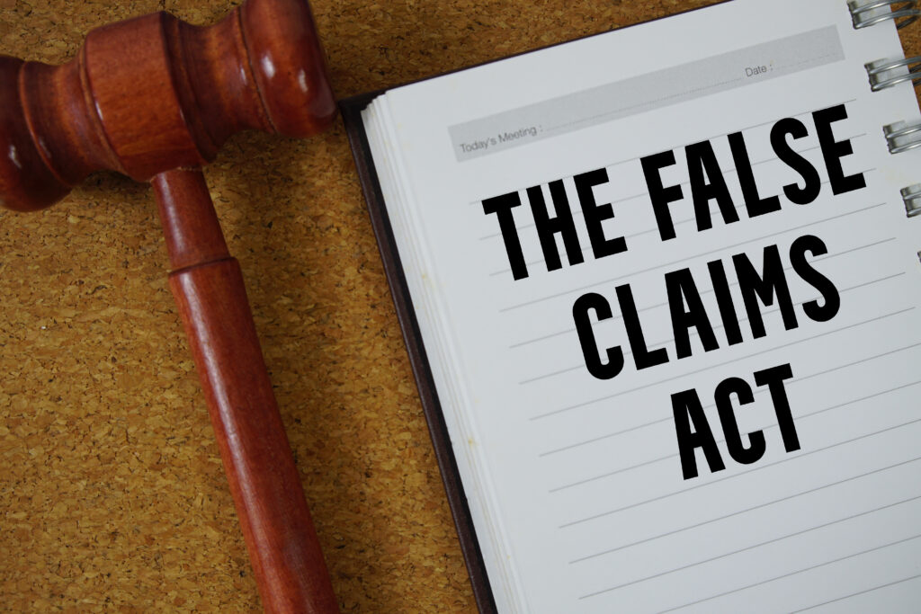 Notebook with the words ‘The False Claims Act’ beside a judge’s gavel.