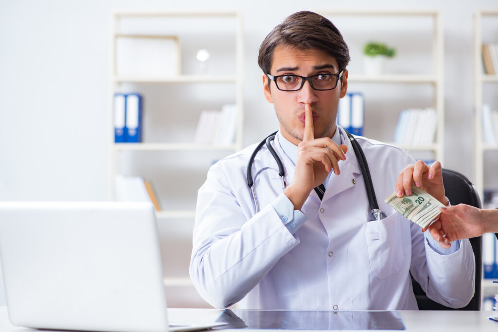Doctor in a white coat reaching toward money being offered.