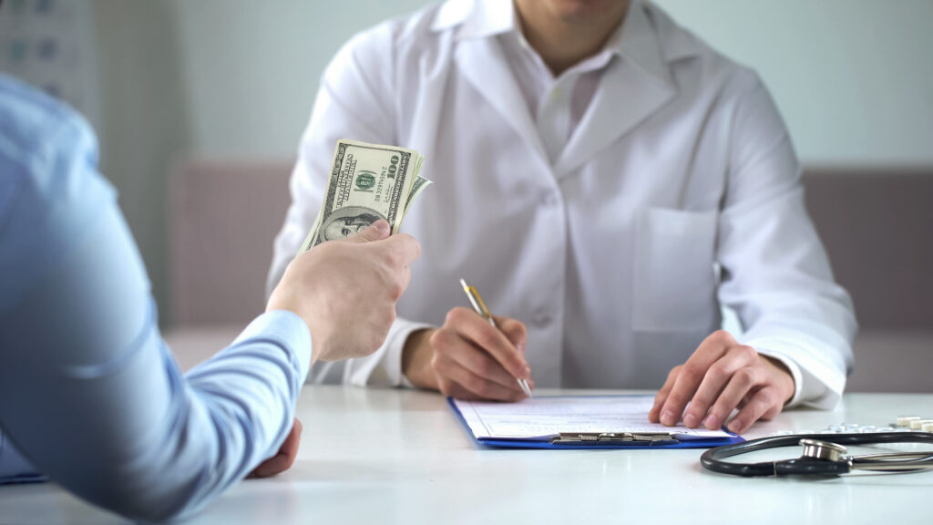 Patient handing cash to a doctor in a clinic.