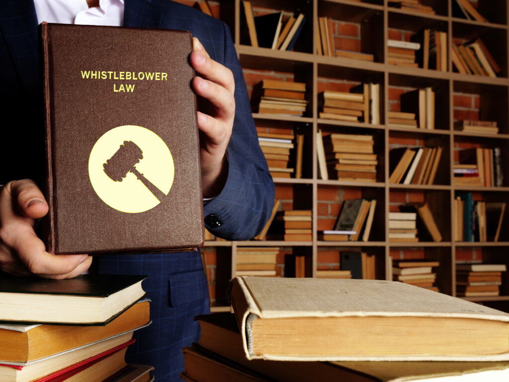 Person holding a legal book titled ‘Whistleblower Law.'
