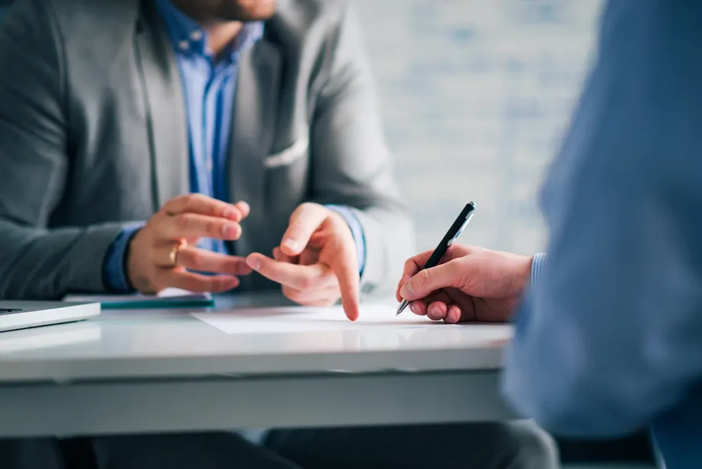 A consultant is sitting down at a conference table with a client, providing services. Healthcare fraud concept.