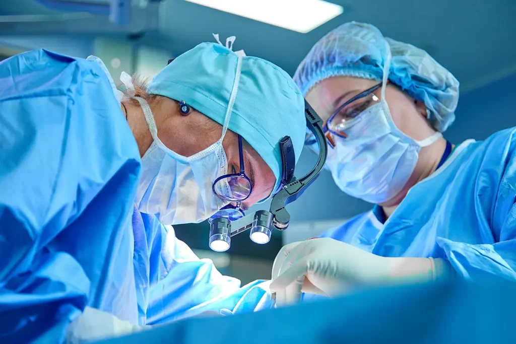 Two surgeons in headgear are working over a patient on a surgical table. Healthcare fraud concept.