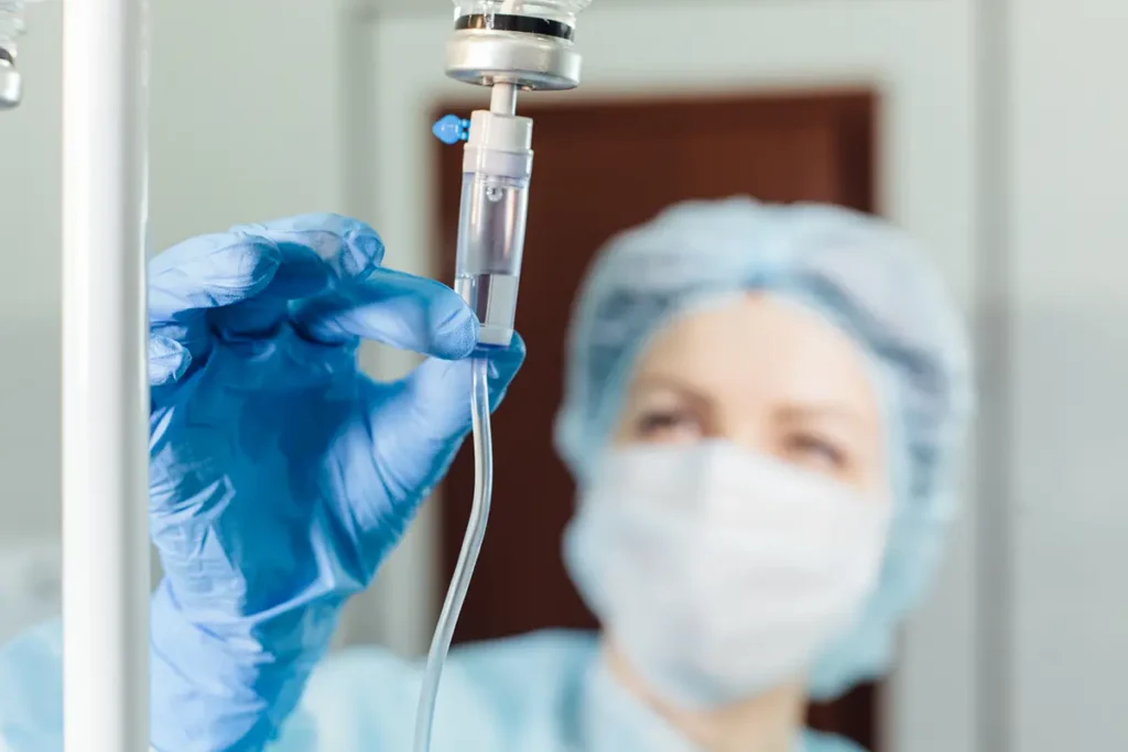 A nurse is checking the medicine inside an IV drip, about to administer it to a patient. Healthcare fraud concept.